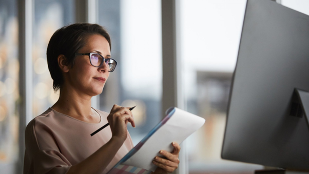 A woman taking down Notes in her Notepad from a computer image